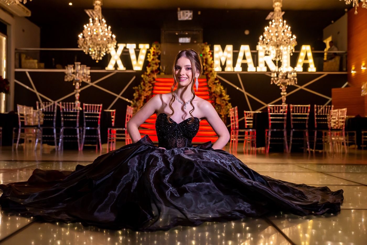 Debutante de vestido preto no salão de festas
